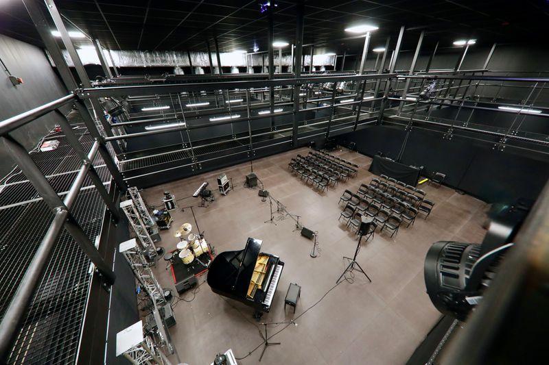 Plateau de tournage du Campus Georges Méliès à Cannes, équipé pour concerts et spectacles : piano à queue, batterie, micros, gradins modulables et passerelles techniques pour son et lumière. Espace idéal pour événements artistiques.