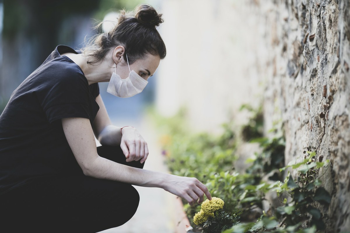 femme avec un masque touchant une fleur 