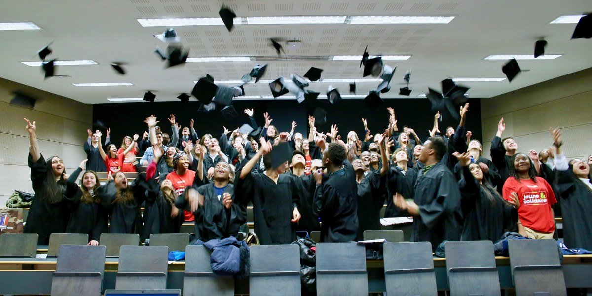 étudiants jetant leurs chapeaux dans un amphithéatre