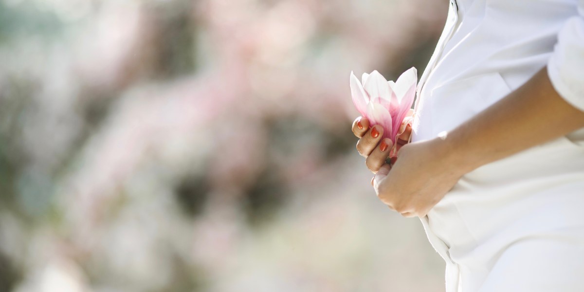 femme enceinte tenant une fleur rose