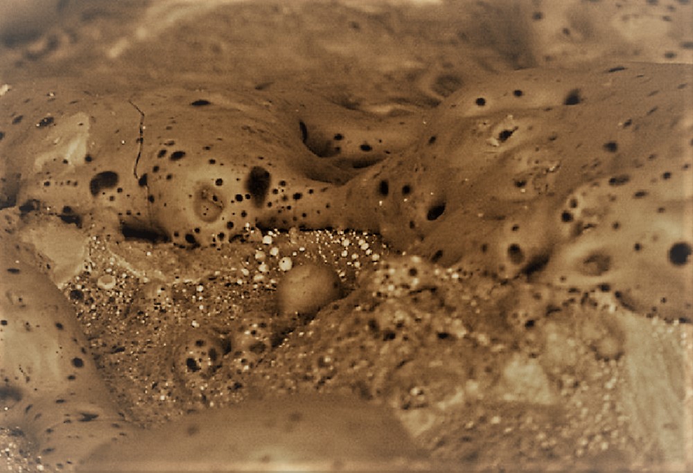 Vue au microscope électronique d'un nappage de verre résultant de l'impact d'une bille de basalte sur une météorite ferreuse. Image colorisée de 250 microns de large. 
